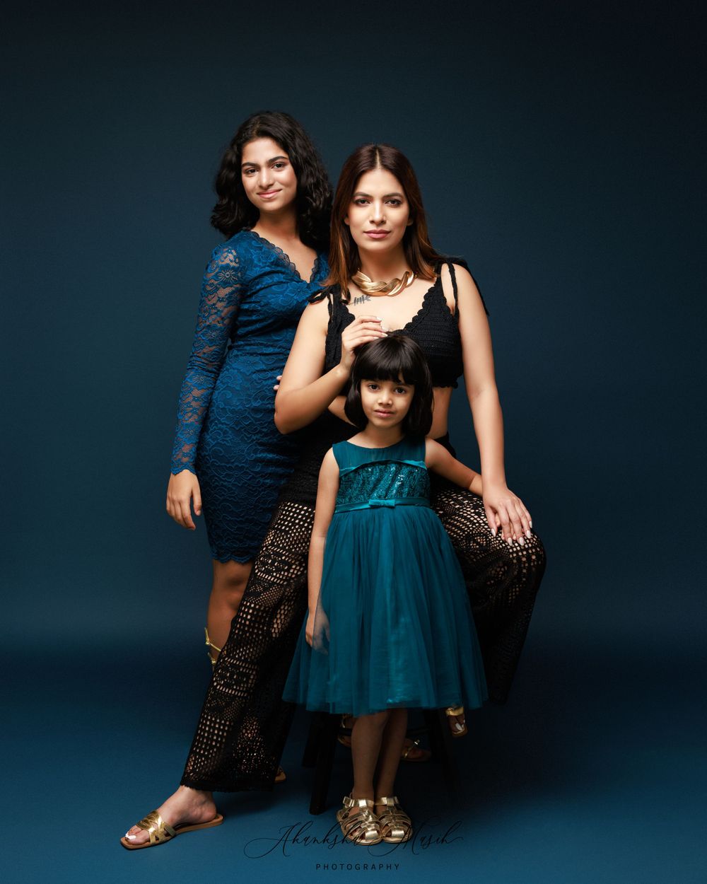Family portrait featuring coordinated blue and teal formal attire against dark background.