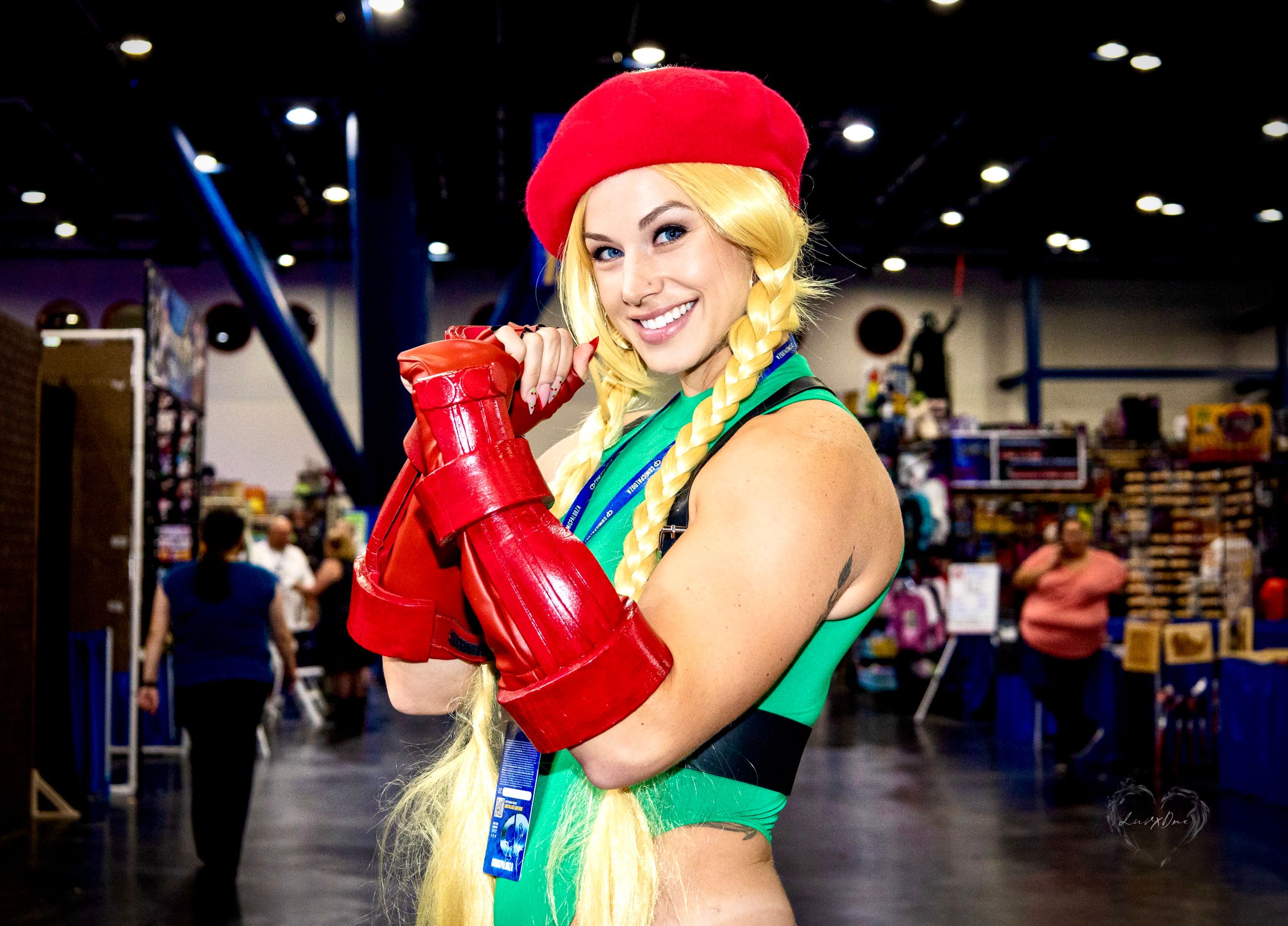 Cosplayer in green and red outfit strikes a pose at comic convention.