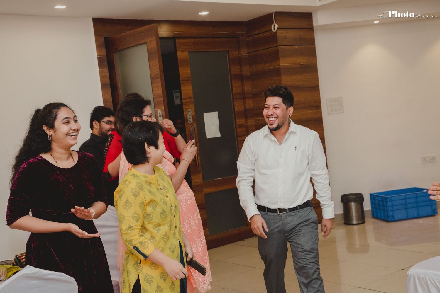 Group dancing and socializing in a modern indoor venue with wood panel walls.