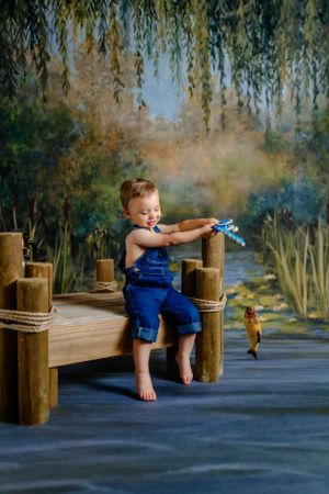 Little boy in overalls sitting on a fake dock, fishing. Delaware Family Photographer