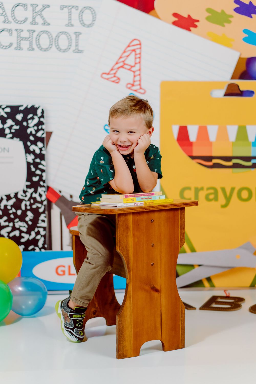 Little boy sitting at a school desk with school supplies behind. Delaware Family Photographer
