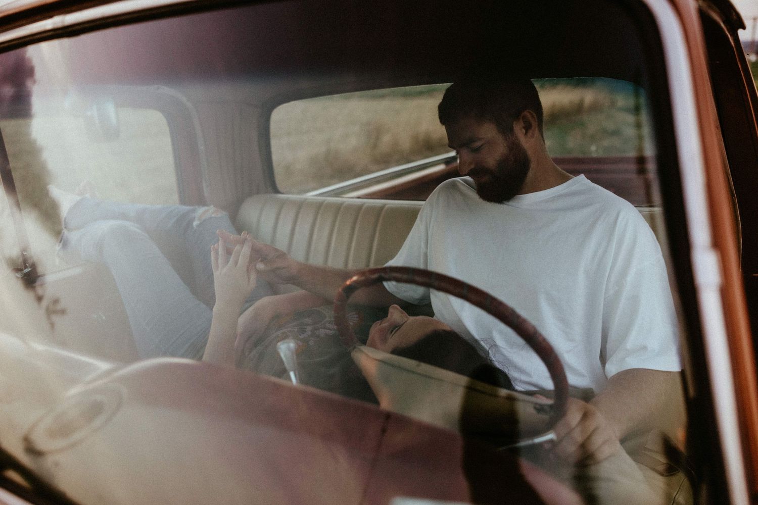 a woman laying on a mans lap in a vintage ford pickup truck