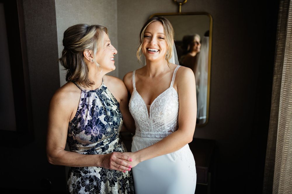 Two wedding party members share a joyful moment in elegant dresses before the ceremony.