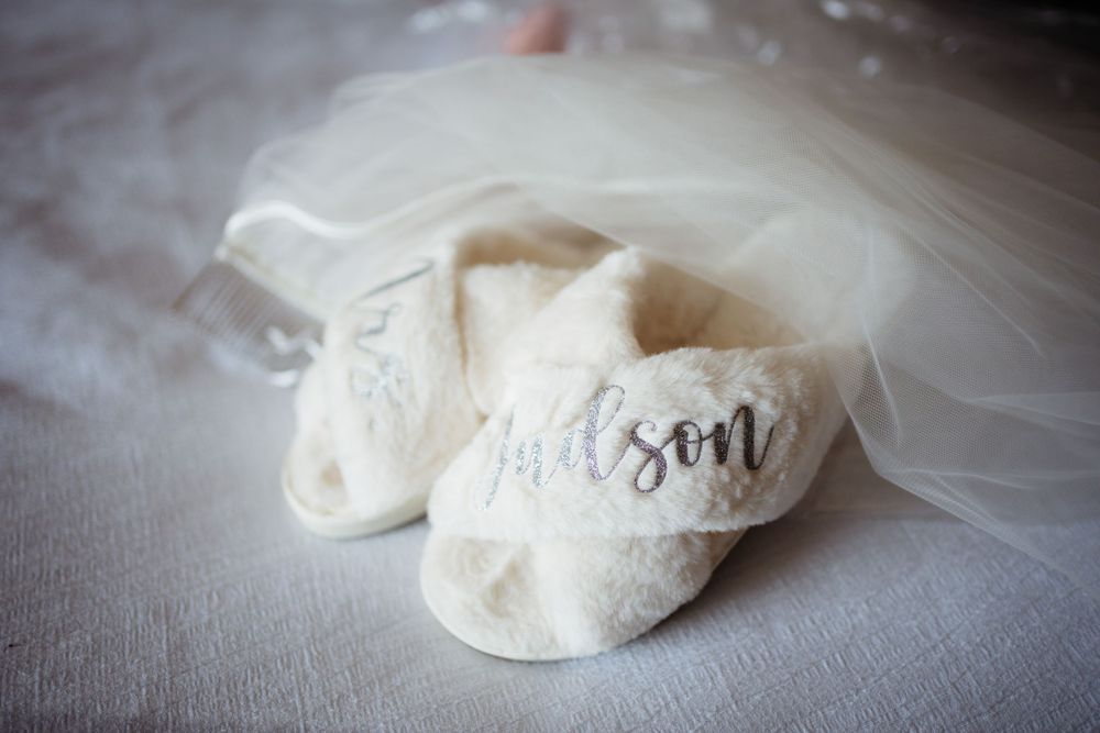 White bridal slippers with 'Mrs' text on soft fabric background.
