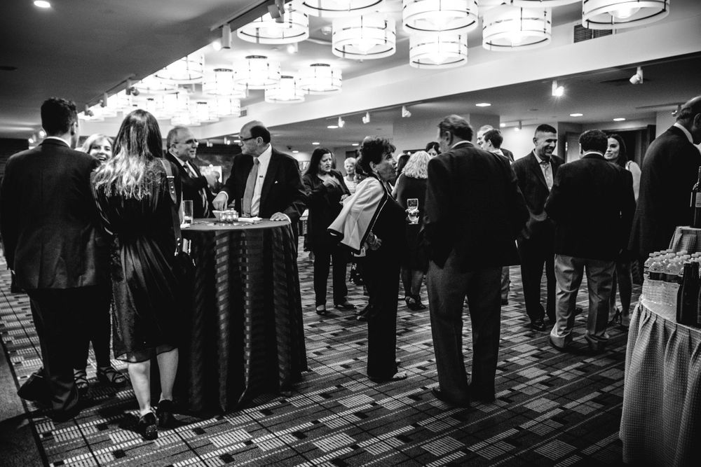 Black and white photo of elegantly dressed professionals networking at a formal corporate event.