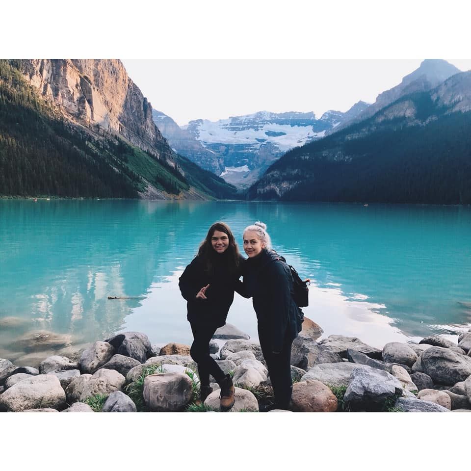A mother and daughter hugging in front of mountains and Lake Louise in Banff National park Alberta, Canada.