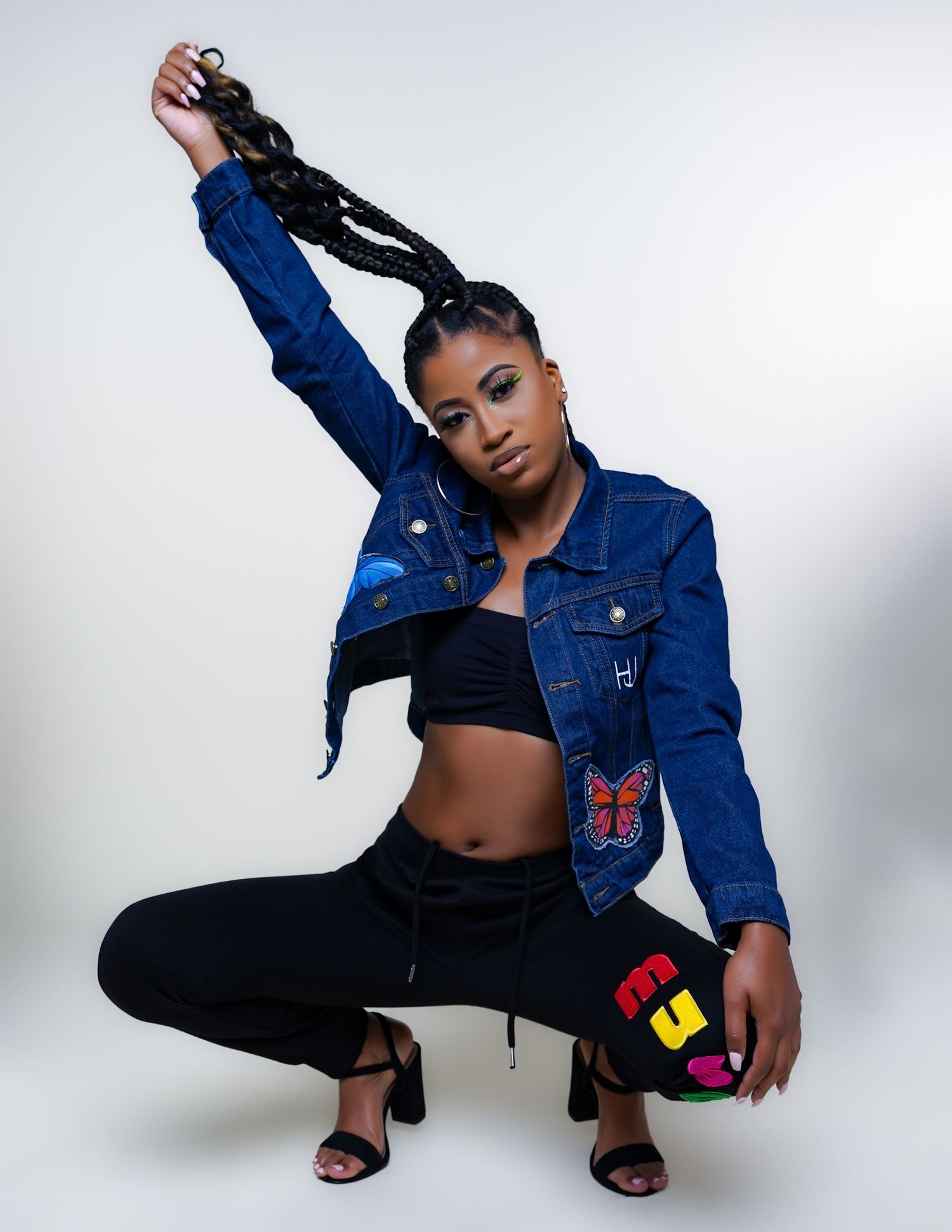 Urban fashion photo with model in denim jacket and black crop top holding basketball.