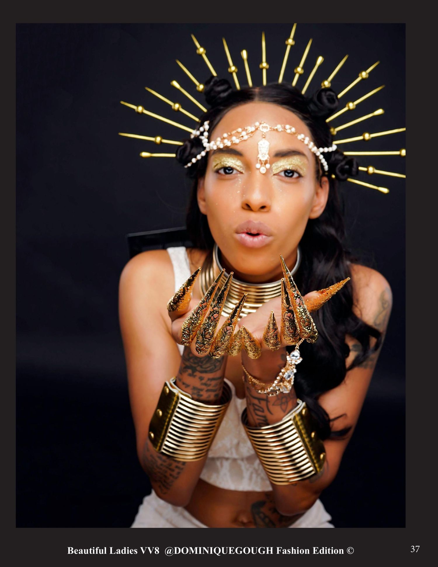 Creative portrait with gold headdress and metallic accessories against dark background.