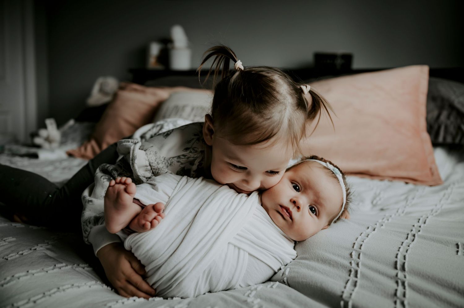 Two siblings share a sweet moment together while lying on a bed.