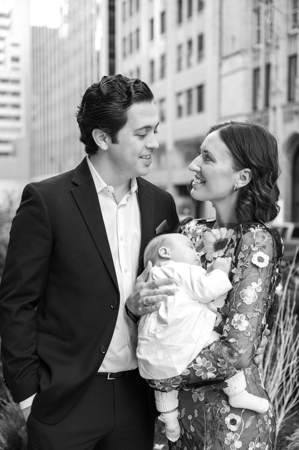 A family portrait in an urban setting with a baby wearing white.