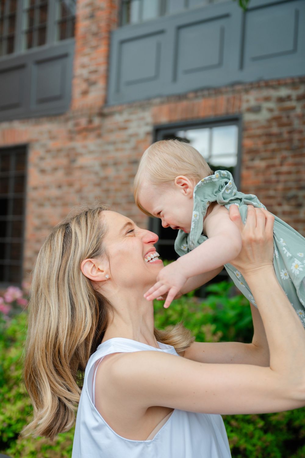 A tender moment of joy between parent and baby against a brick building backdrop.
