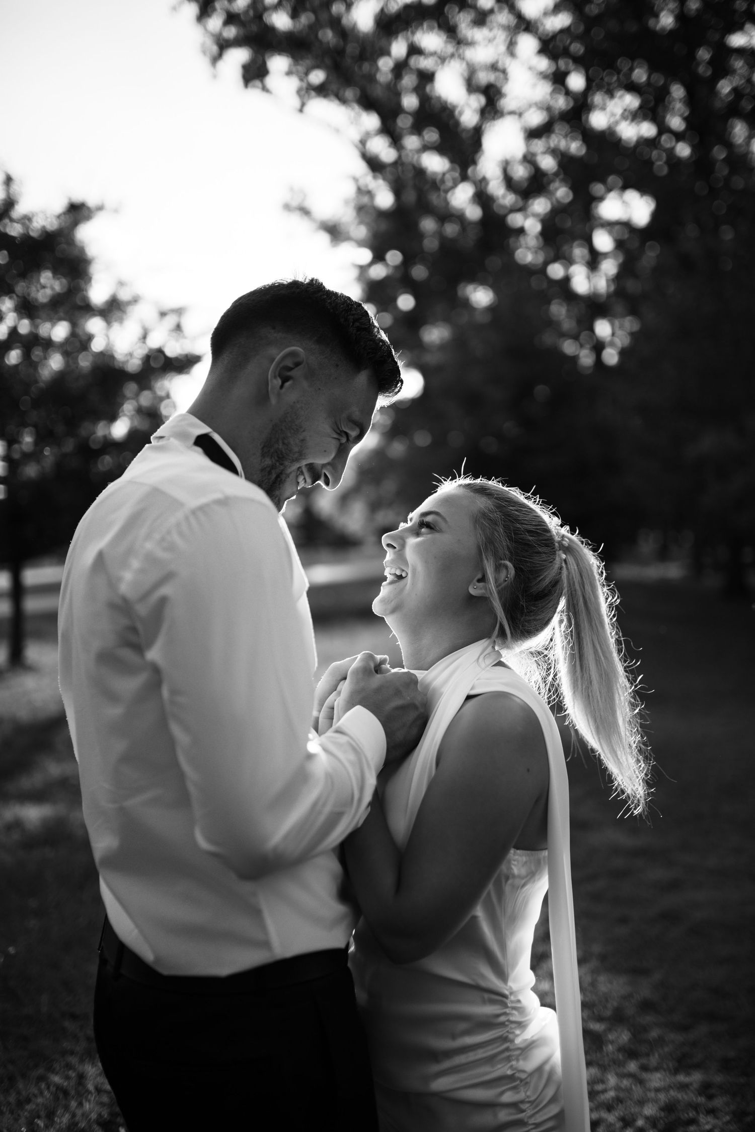 An intimate black and white portrait of a joyful couple sharing a tender moment outdoors.
