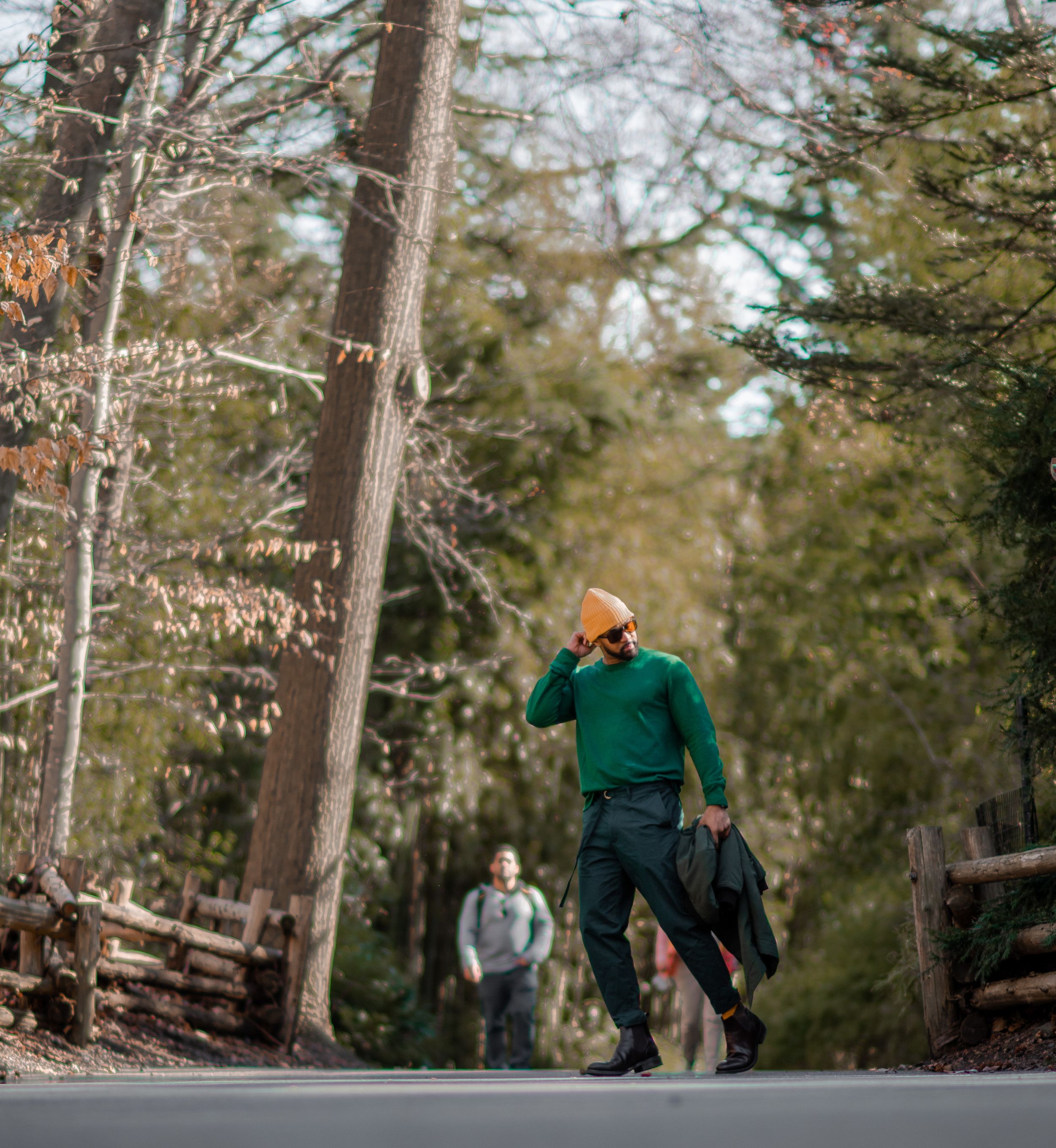 People walking through a wooded forest path during an autumn day.