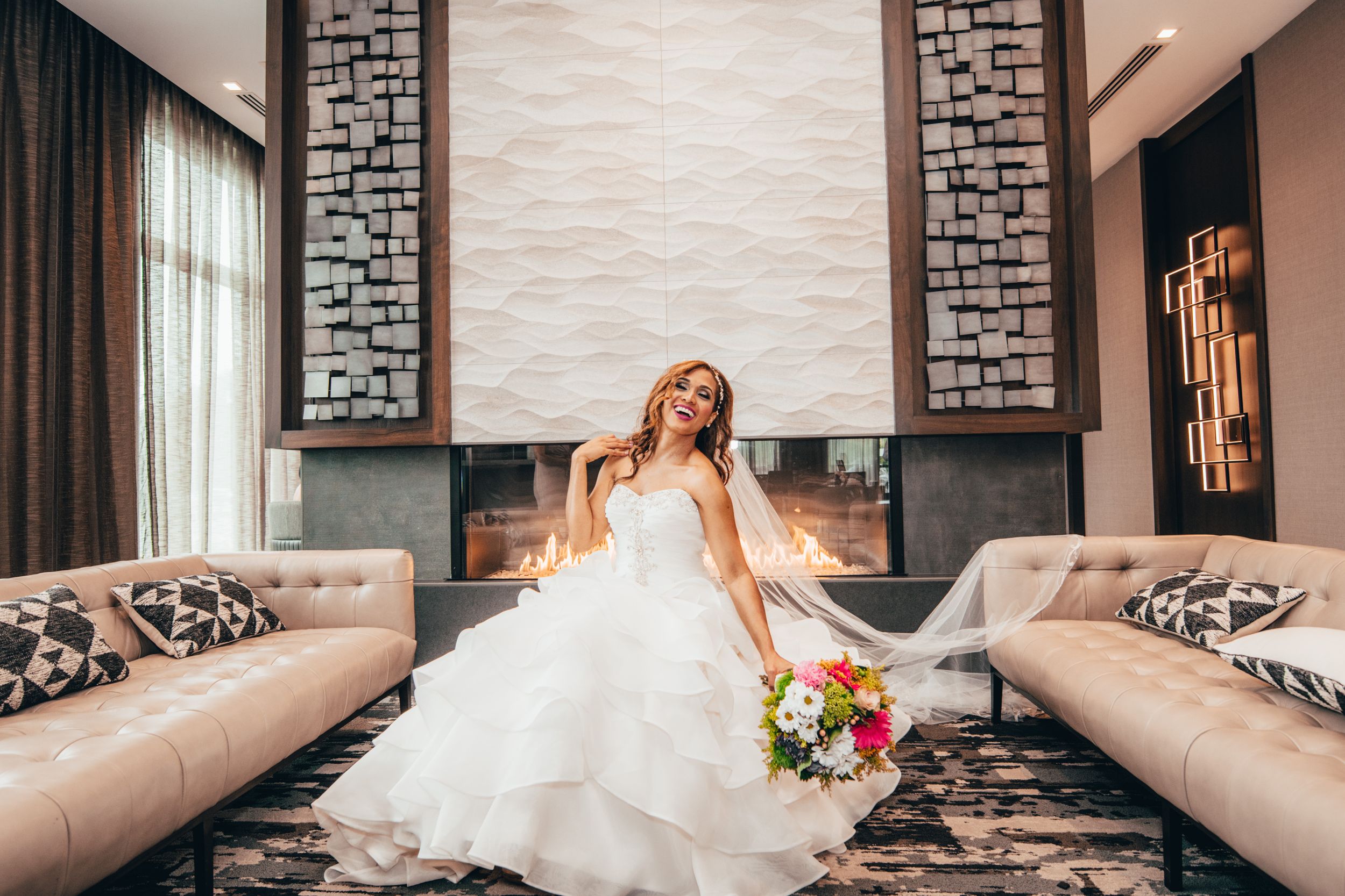 An elegant bridal portrait on a tufted couch with stone accent walls and natural lighting.