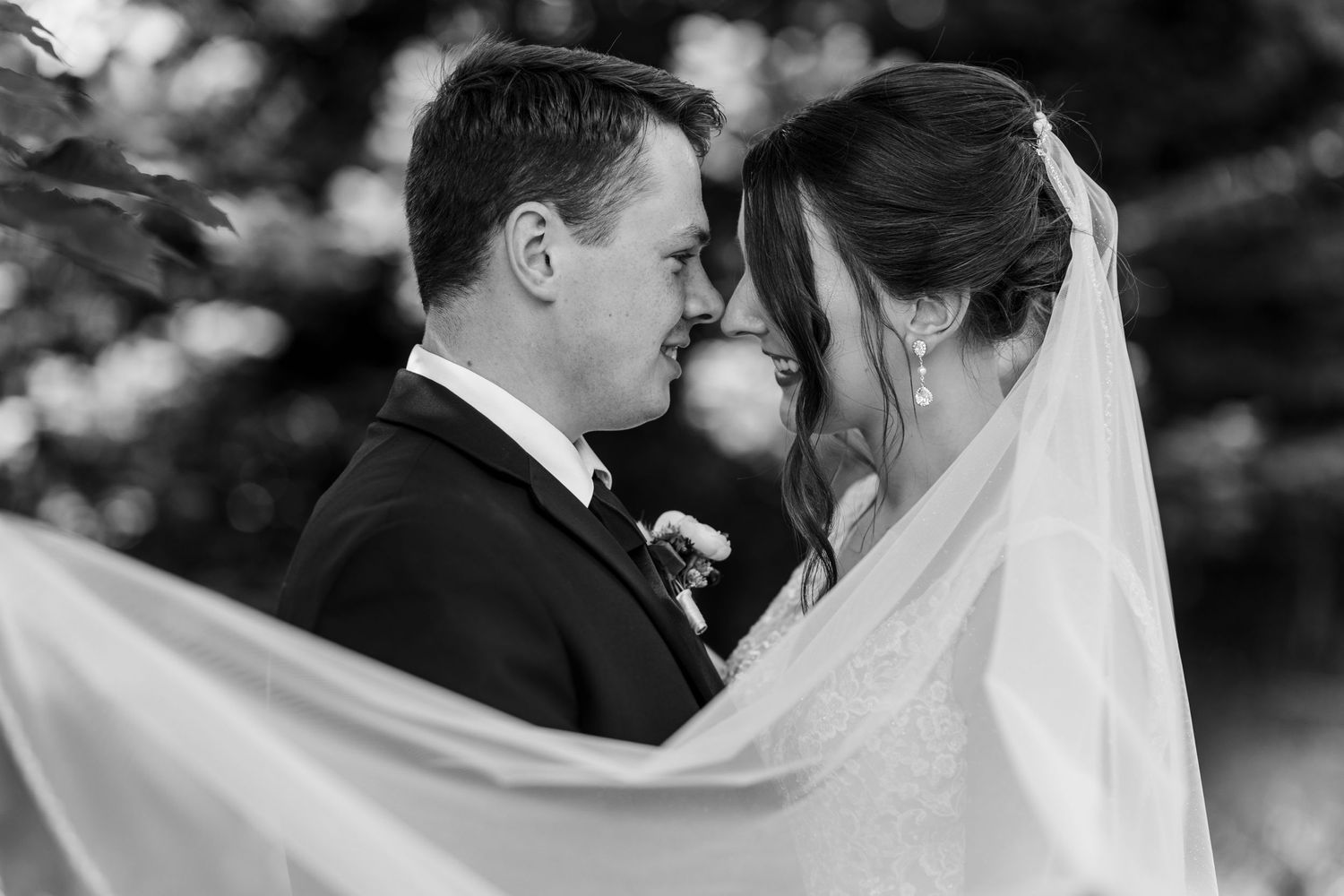 Black and white wedding portrait featuring bride and groom with elegant flowing veil.