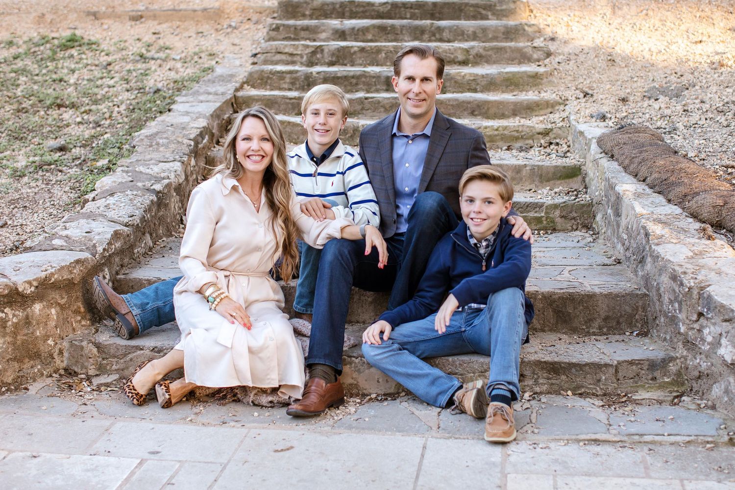 Family sitting together on rustic stone steps in coordinated casual outfits.
