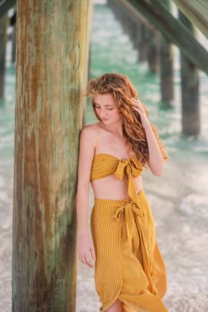 senior in front of pier on beach during senior portrait beach session at sunset on Panama City Beach Florida