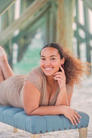 senior in front of pier on beach during senior portrait beach session at sunset on Panama City Beach Florida
