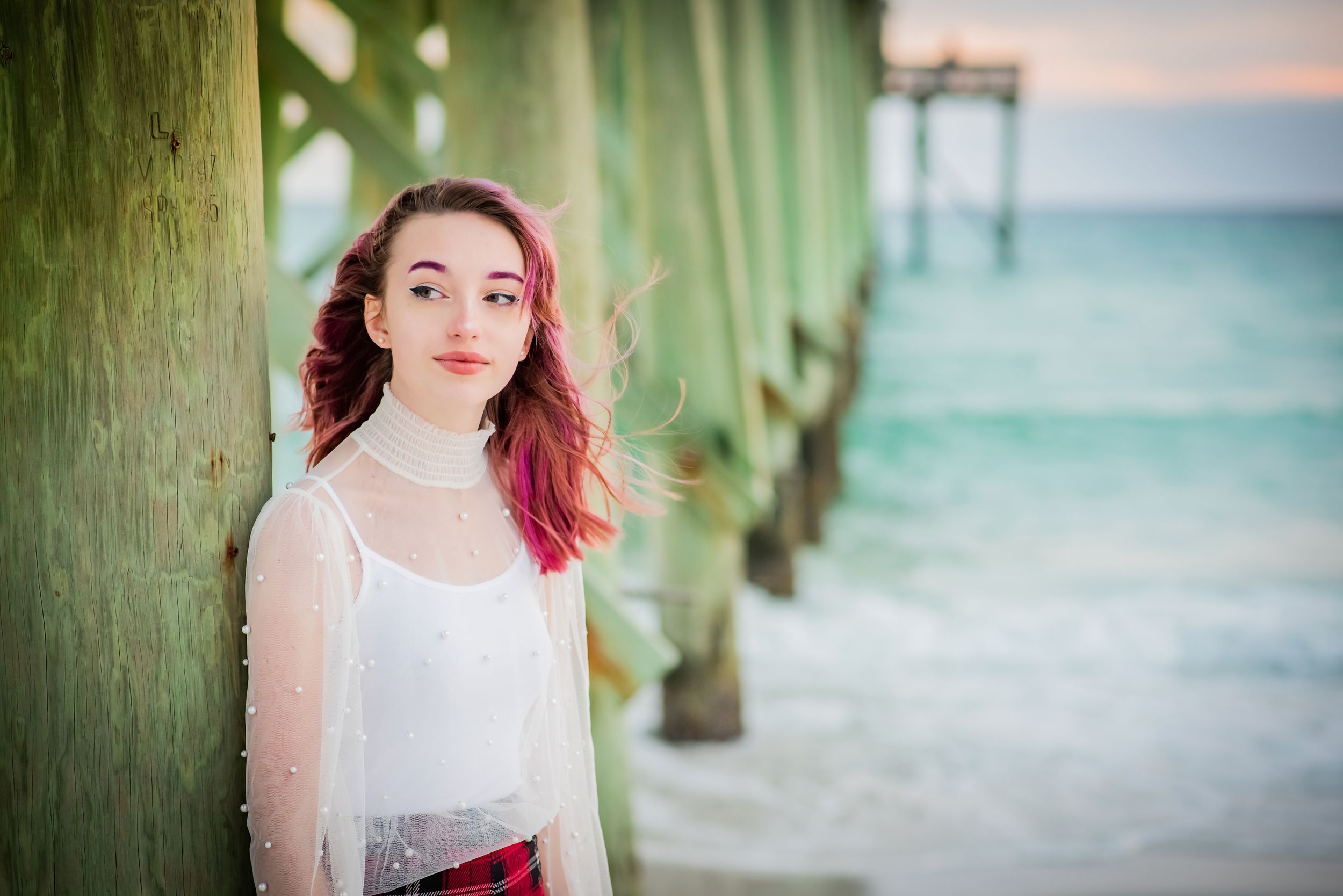 senior in front of pier on beach during senior portrait beach session at sunset on Panama City Beach Florida