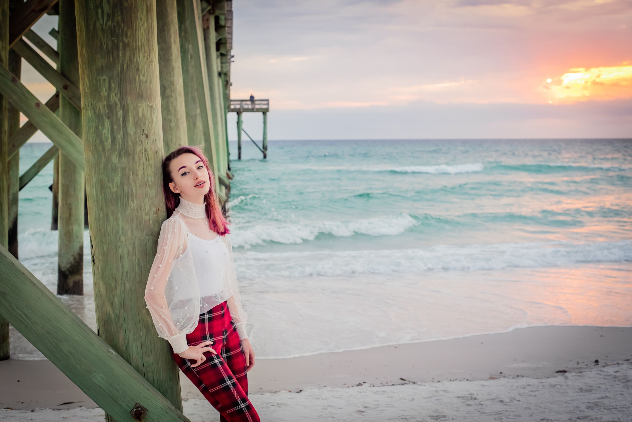 senior in front of pier on beach during senior portrait beach session at sunset on Panama City Beach Florida