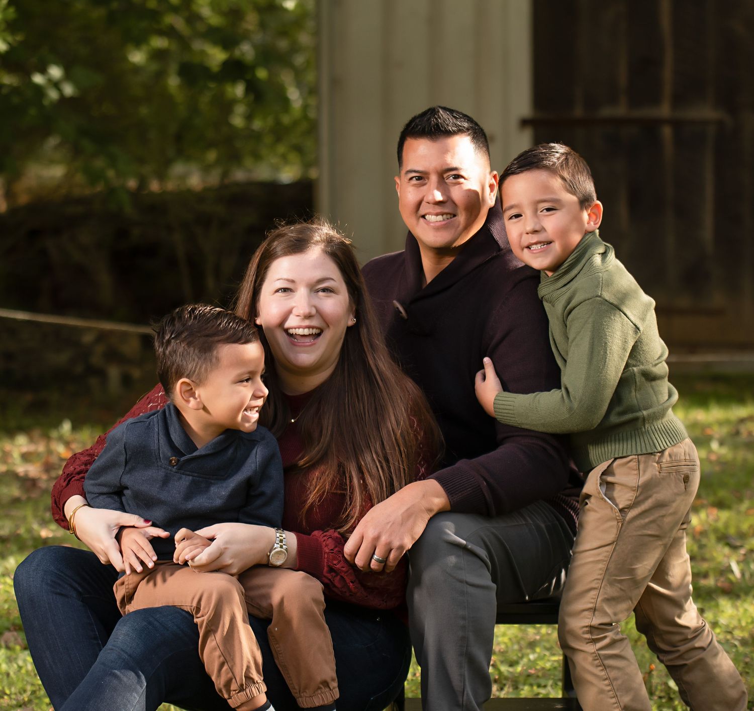 A family of four shares a joyful moment together outdoors in autumn.