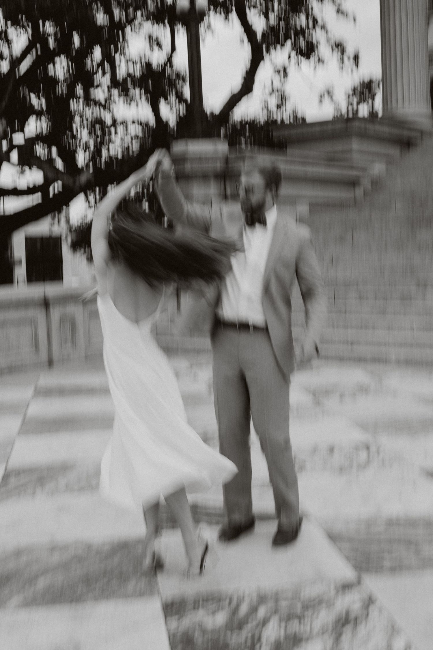 A black and white motion blur photo of a man twirling his fiance