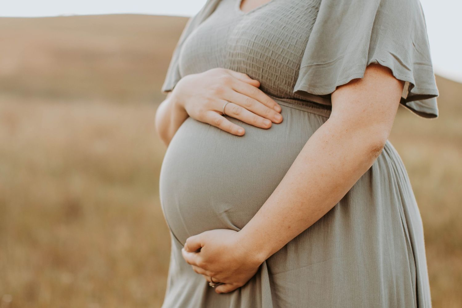 Maternity photography featuring gentle embrace and soft natural lighting.