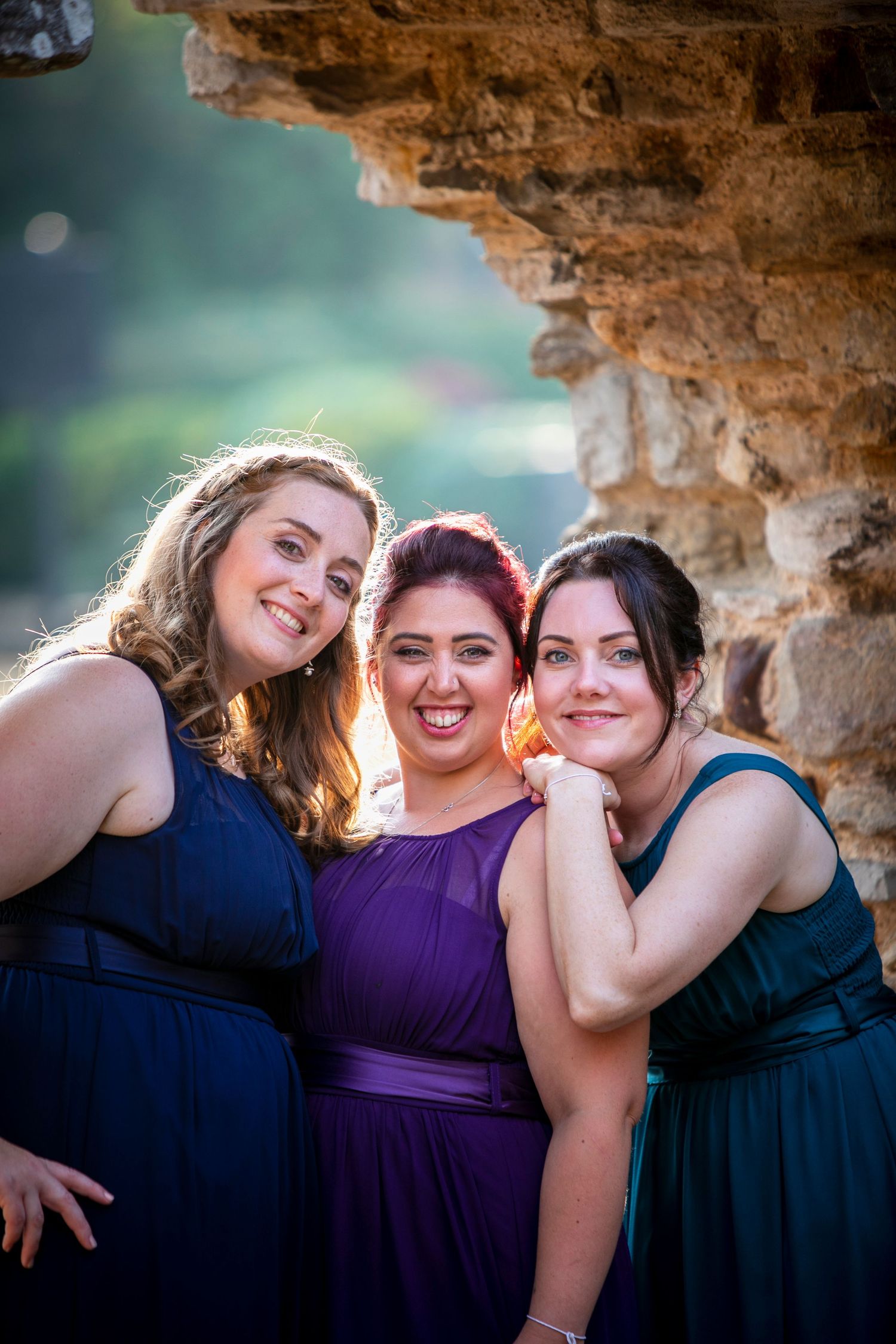 Friends share joyful moments while posing together under a rustic stone archway.