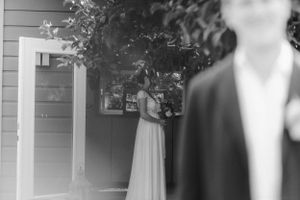 Black and white photo showing a wedding scene through branches and leaves.