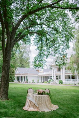 White colonial style house with a decorated sweetheart table on the front lawn.
