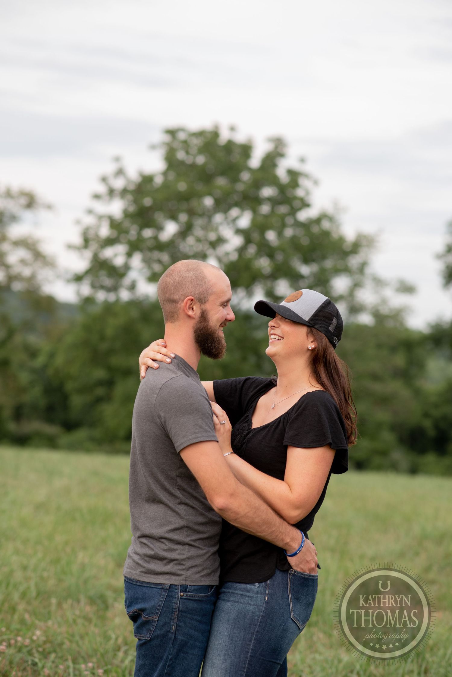 A joyful couple laughing together in a sunny meadow.