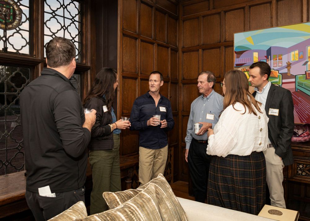 Business networking event in an elegant wood-paneled room with casual conversation.