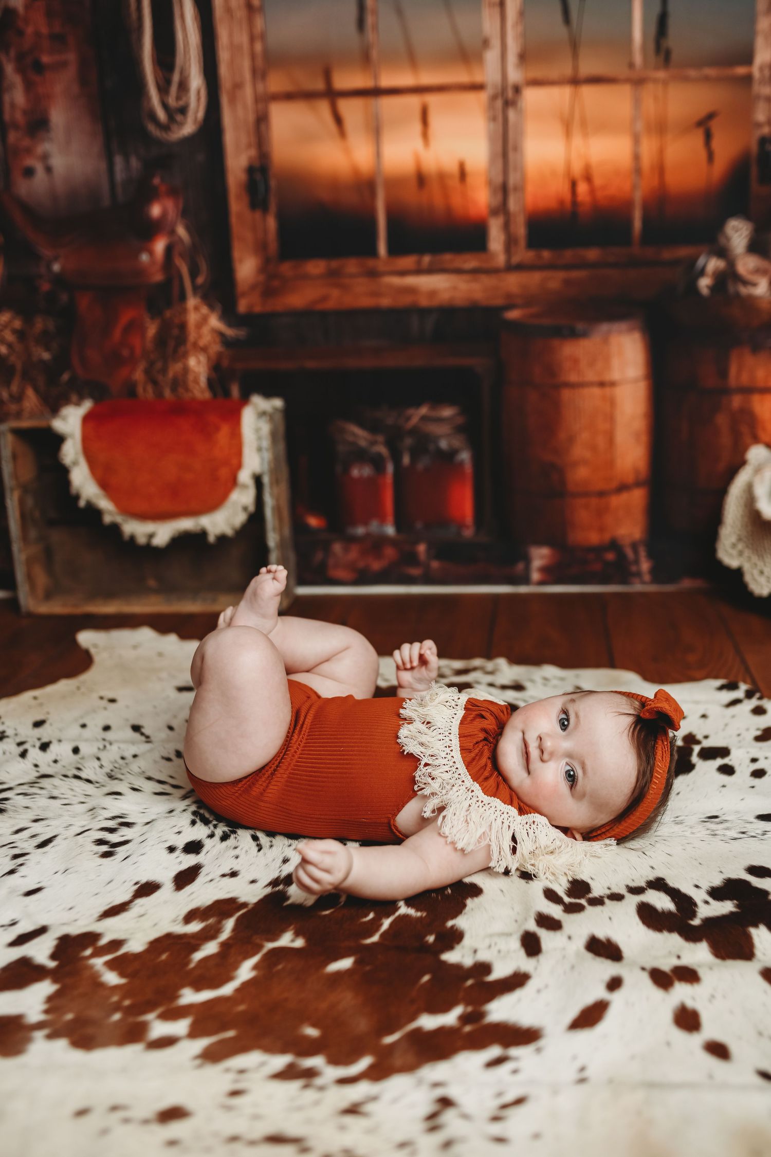 Baby in red outfit lying on white lace blanket with scattered coffee beans.