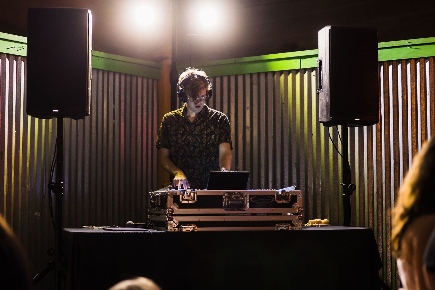 DJ booth setup with green accent lighting at an evening wedding reception.