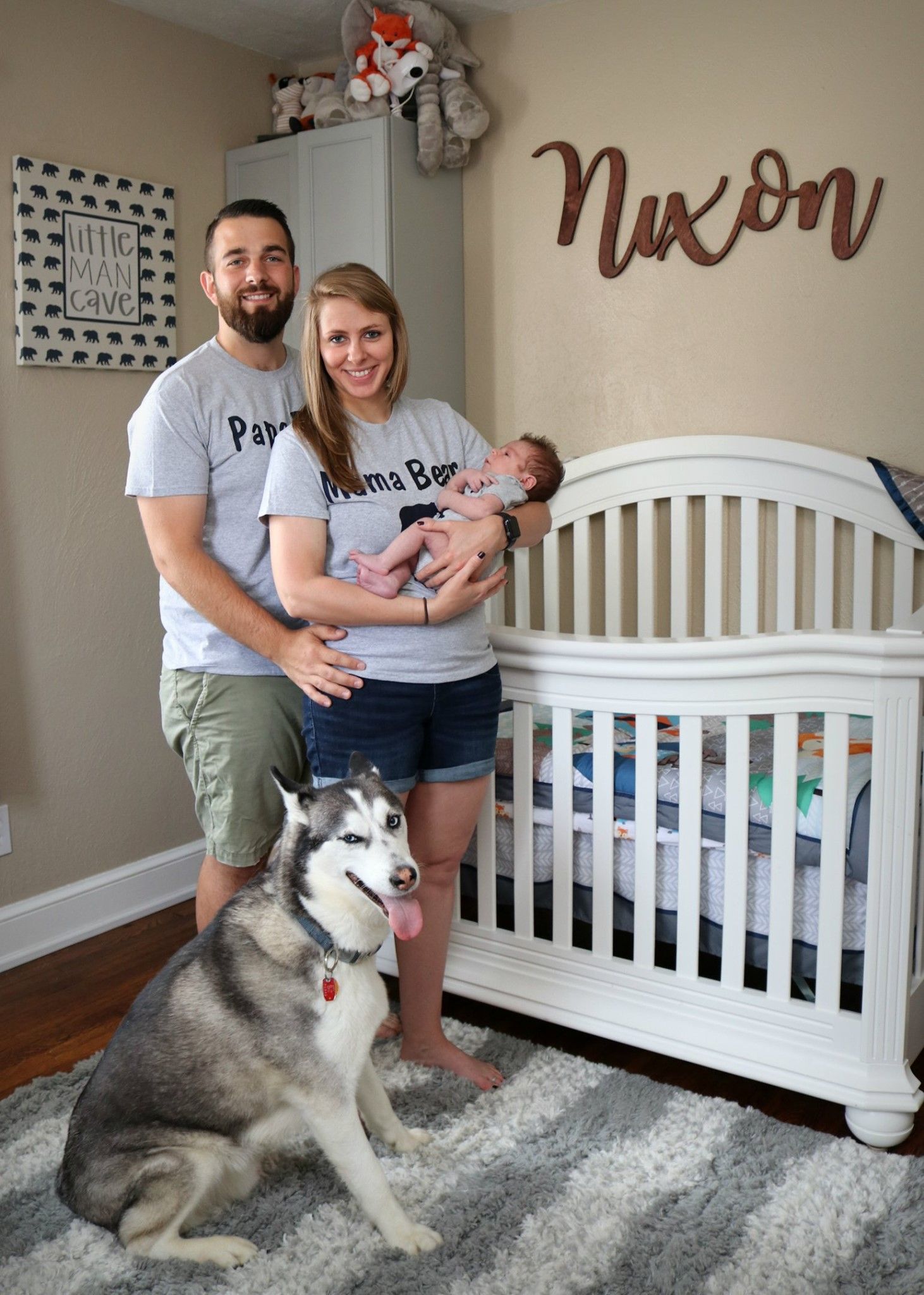 A nursery room with a white crib, husky dog, and a wooden 'Nixon' sign on the wall.