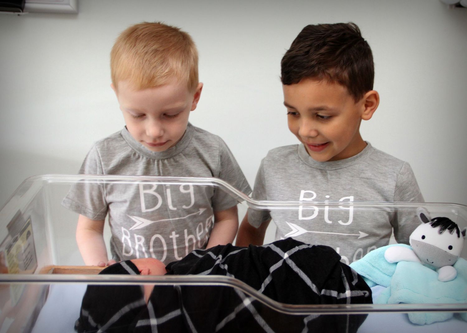 Two children reading a book together wearing matching Big Brother shirts.
