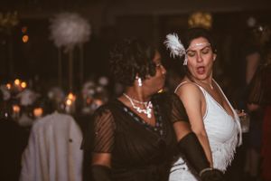 Dancers in 1920s-style outfits and feather headpieces perform at a vintage-themed party.