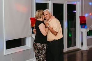 A couple dancing together at an indoor event with colorful lighting.