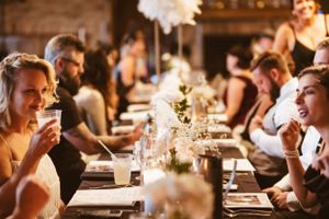 Guests dining at an elegant candlelit table with white feather centerpieces.