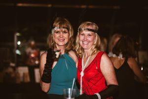 Two guests in formal attire smiling and posing together at an evening event.