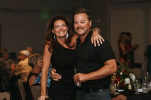 A couple posing together at a social event wearing matching black outfits.