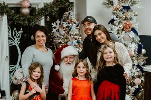Group holiday portrait in front of decorated Christmas tree with Santa Claus and festive decorations.