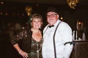 Couple in formal black and white attire poses at a Gatsby themed celebration.