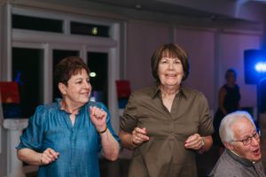 Guests dancing and enjoying themselves at an indoor party with blue lighting.