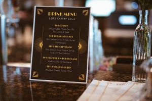 An elegant black and gold menu card displayed on a wooden table.