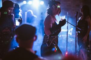 Party guests in vintage costumes dance and socialize at a 1920s themed celebration.