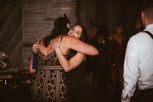 Two partygoers share an emotional embrace on the dance floor at an evening celebration.