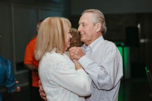 Two people dancing together at an evening social event with dim lighting.