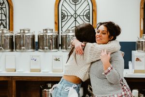 Two people sharing a warm embrace in front of decorative glass storage containers.