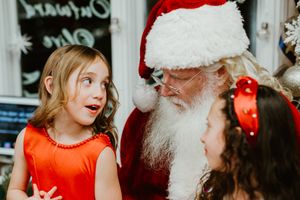 Excited children interact with Santa Claus during holiday celebration.